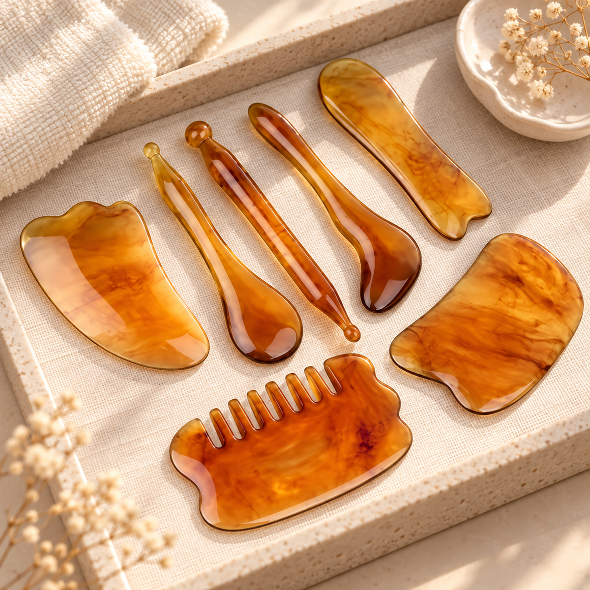 Amber face and body gua sha massage set arranged on a neutral vanity tray